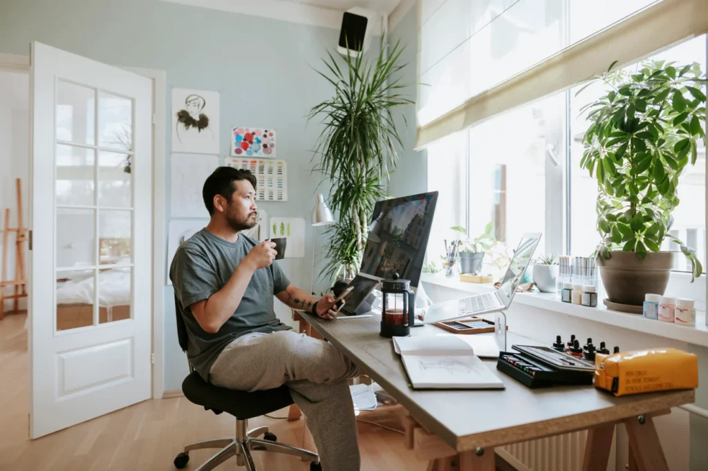 A man sitting in his home office with a coffee in front of his computer