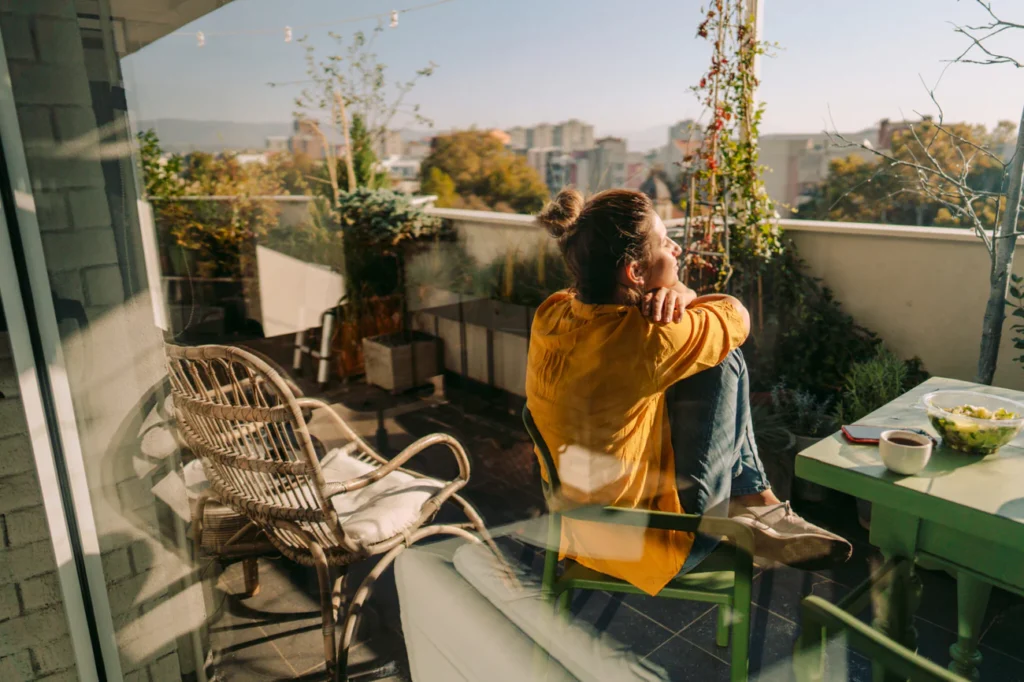 A woman seated on a chair in her balcony looking out to the sky