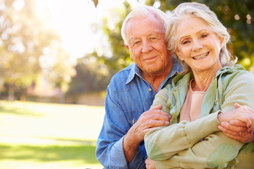 An elderly couple outside in a loving embrace